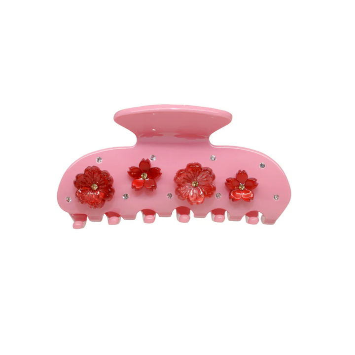 Pink hair clip with red floral designs on a white background